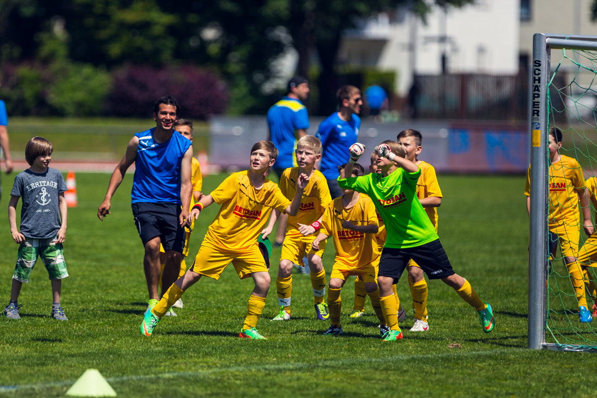 Kinder beim gemeinsamen Fußballtraining; ein Torwart und mehrere Spieler interagieren am Tor.