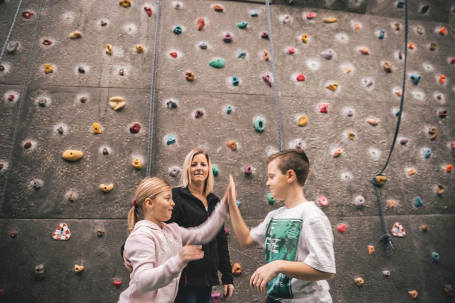 Zwei Kinder klatschen sich ab, im Hintergrund eine Trainerin