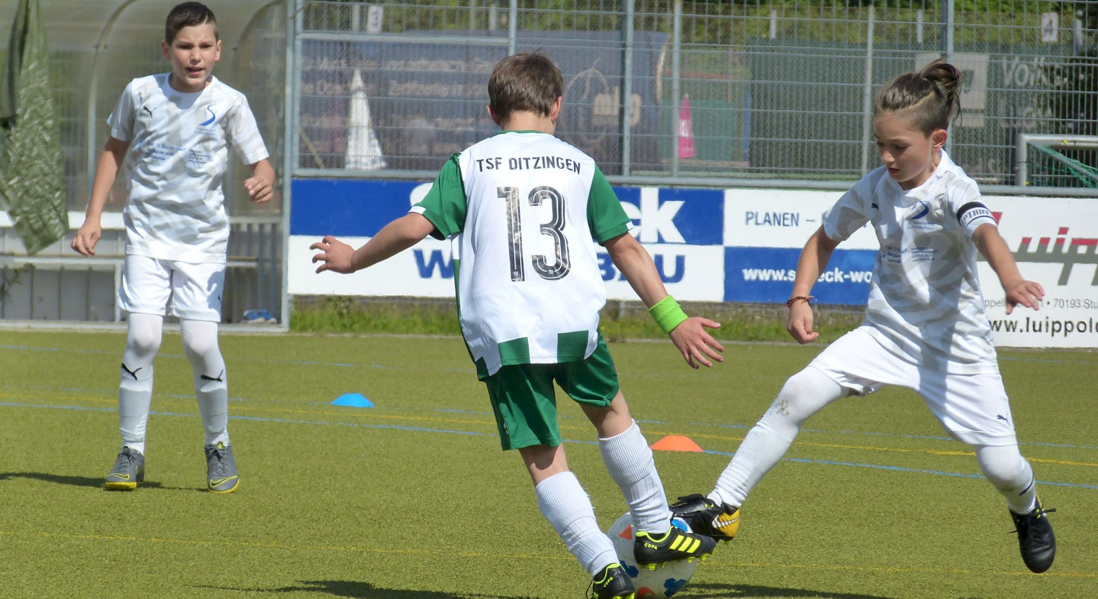 Drei Jugendfußballer kämpfen im Spiel um den Ball auf dem Spielfeld.