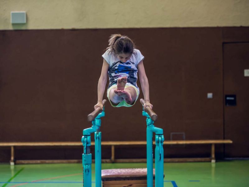 Junge Turnerin am Reck die beine in der horizontalen