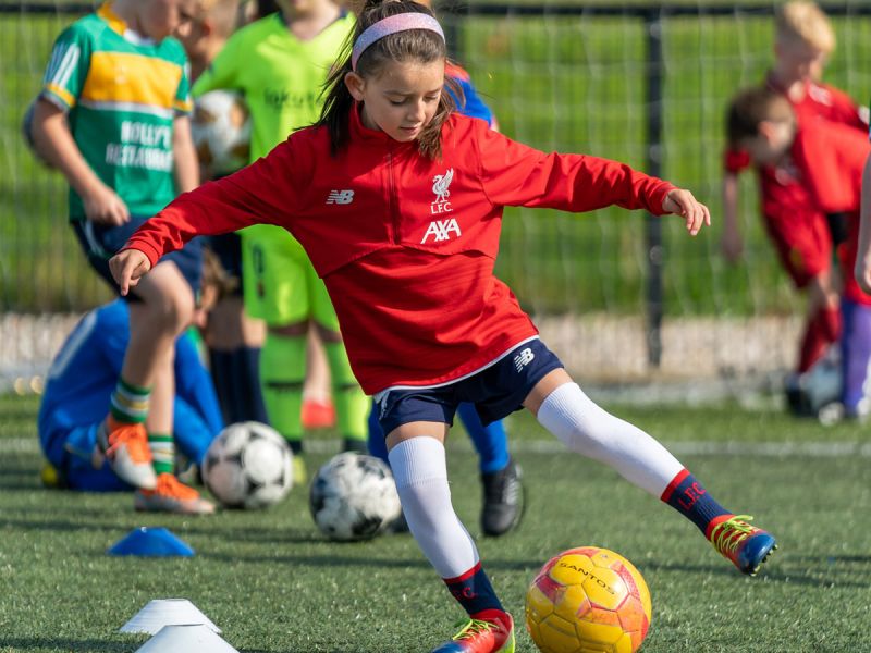 Junge Fussballerin nimmt den gelben Ball geschickt an